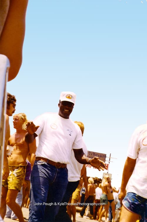 Man in a white polo and cap in the crowd