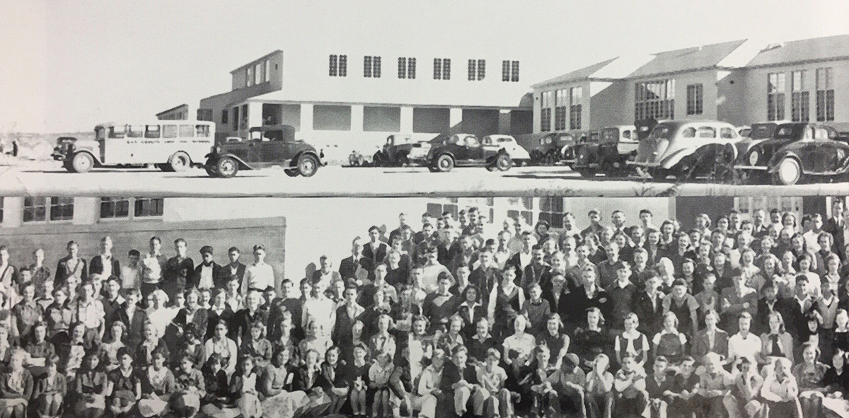 Two-story school buildings with a school bus and 1930s cars parked in front, above a second photograph of the student body seated and standing in rows