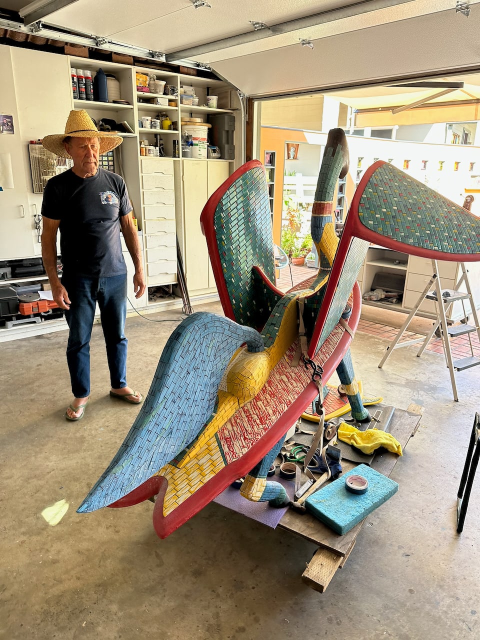 The large winged mosaic creature seen from the other side, wings tiled in blue and green