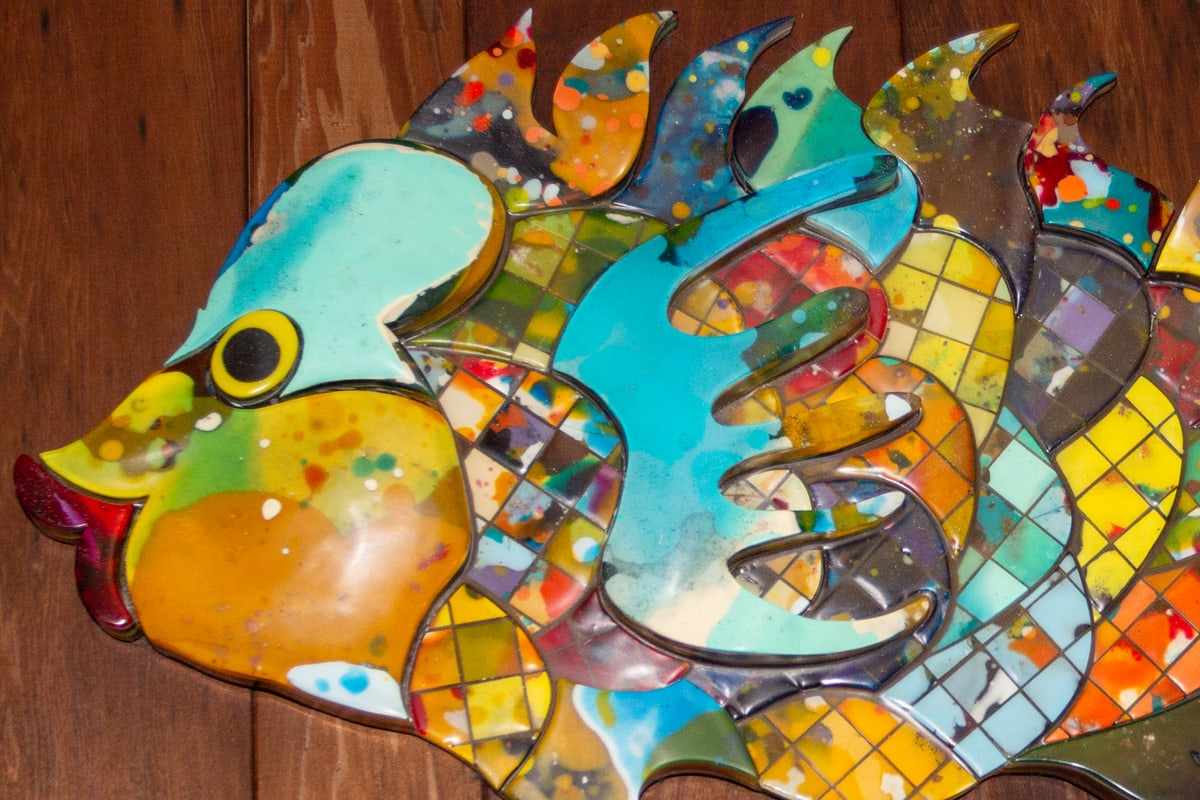 Close-up of the fish sculpture's head, showing a turquoise crown, a yellow-ringed black eye and deep red lips