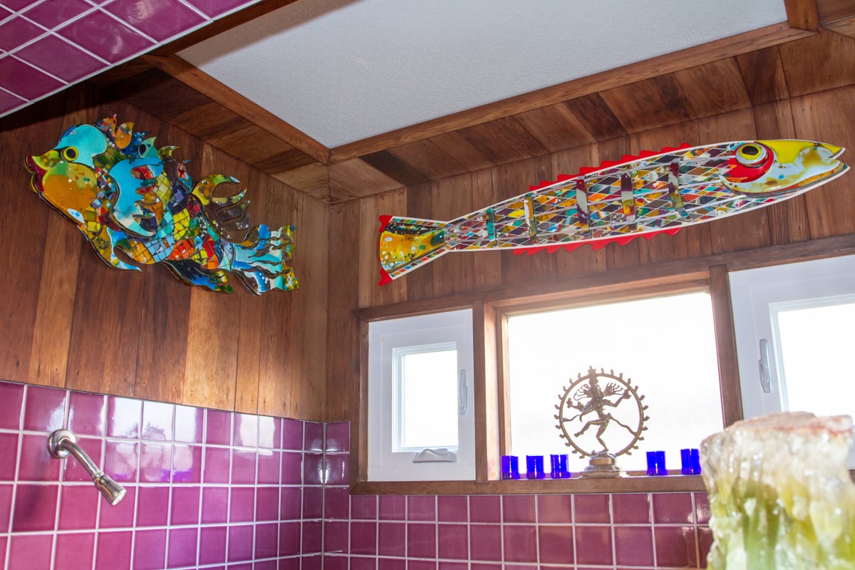 Two resin fish sculptures mounted high on a wood-panelled wall above purple tile
