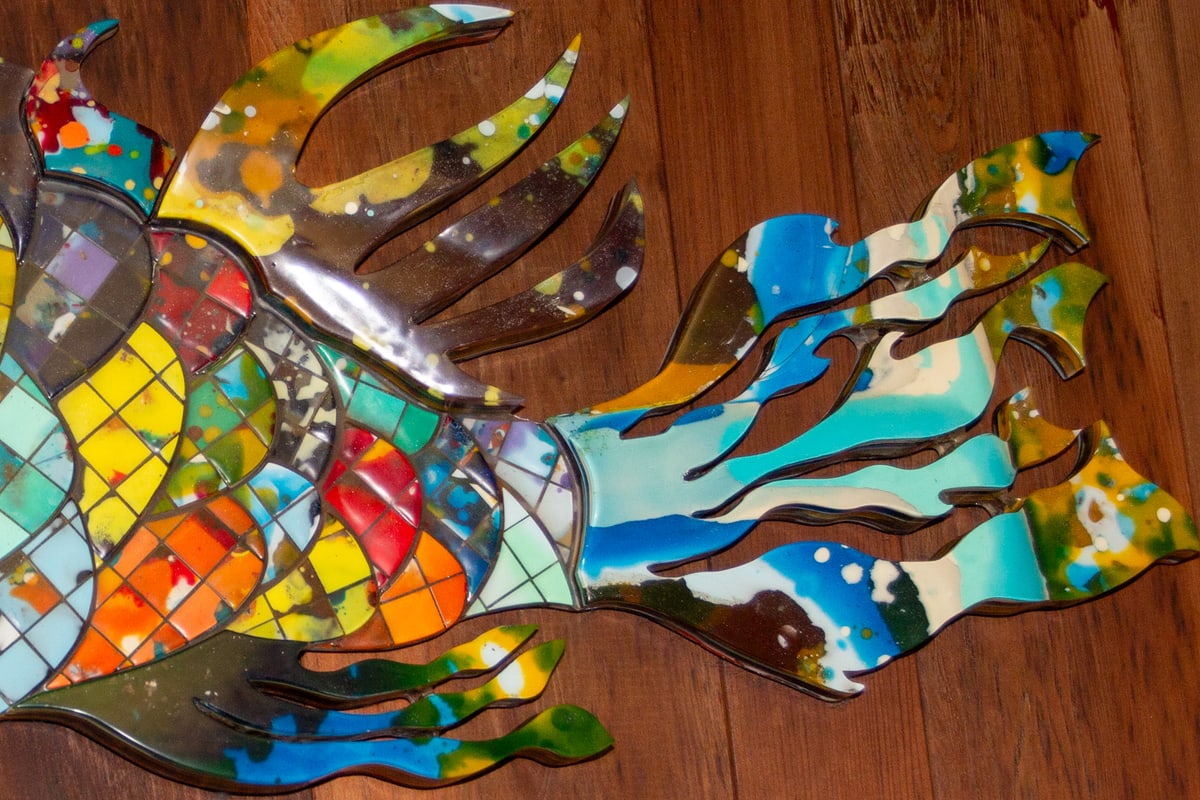 Close-up of the fish sculpture's tail, mosaic tiles giving way to sweeping blue and green resin fins