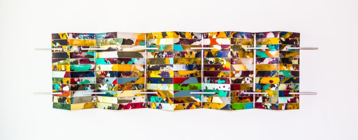 A long folded wall panel of mosaic tiles cut from multicoloured recycled surfboard resin