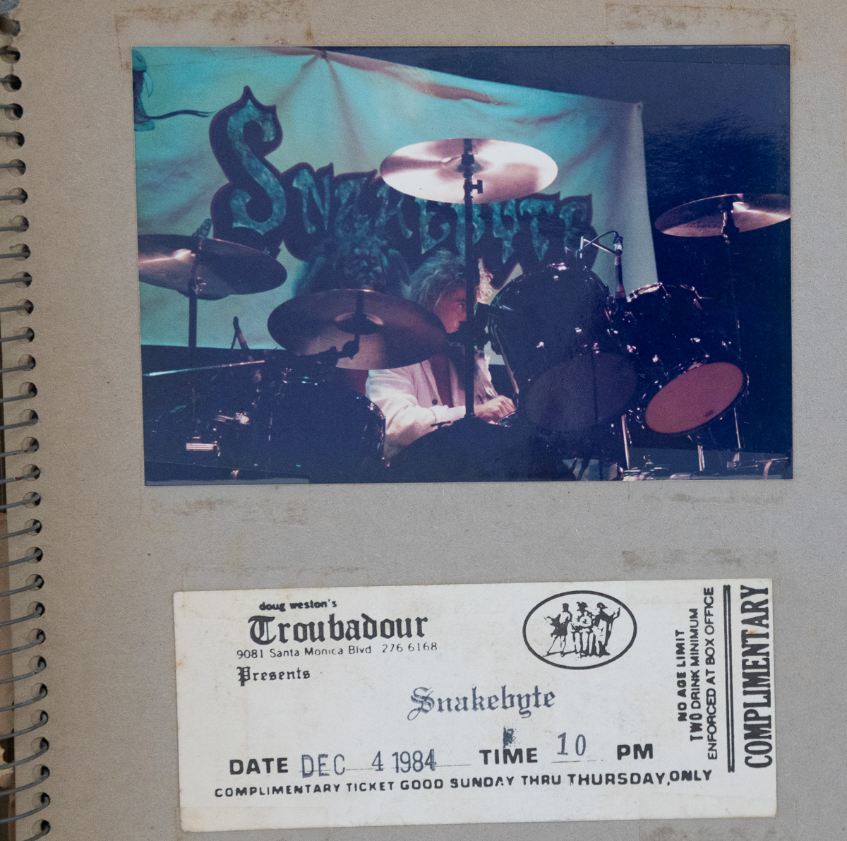 A scrapbook page with a colour photograph of a drummer under a Snakebyte banner above a Troubadour concert ticket