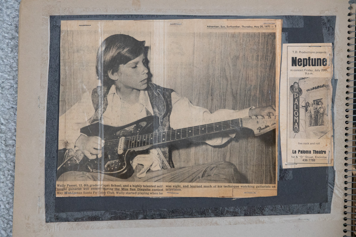 A 1971 newspaper clipping in a scrapbook showing a young Wally Passet playing an electric guitar, beside a La Paloma Theatre concert flyer