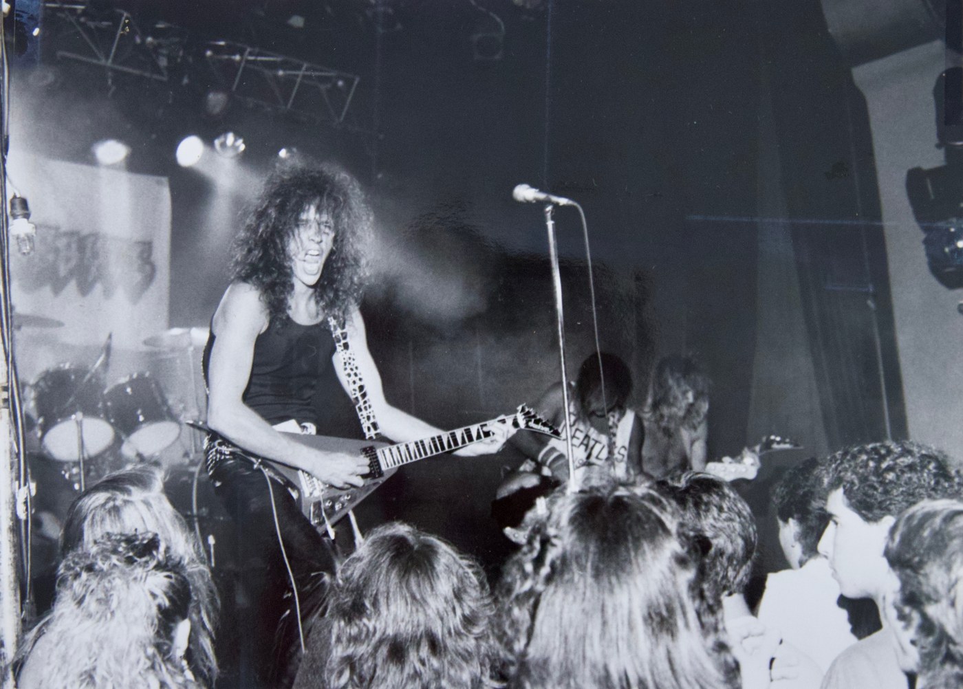 Wally Passet screaming into the microphone playing a Flying V guitar above the crowd, La Paloma Theater 1996