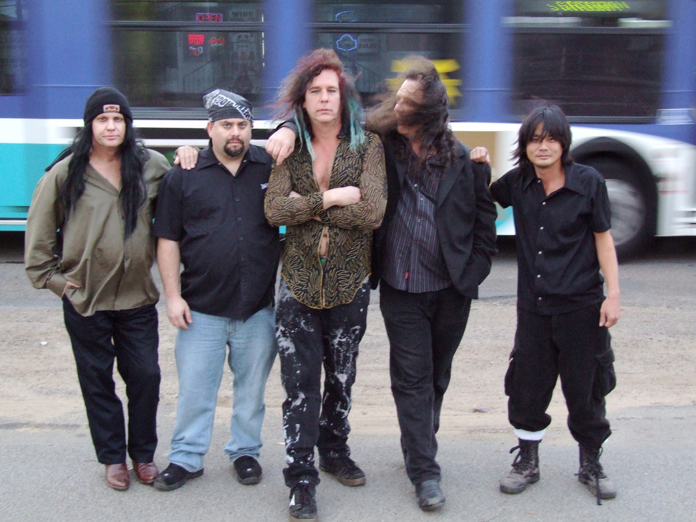 The five members of Wally World standing in the street as a city bus blurs past behind them