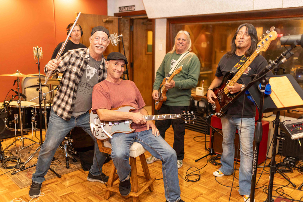 The Johnny Rock Band posed together in the rehearsal room, laughing, instruments in hand