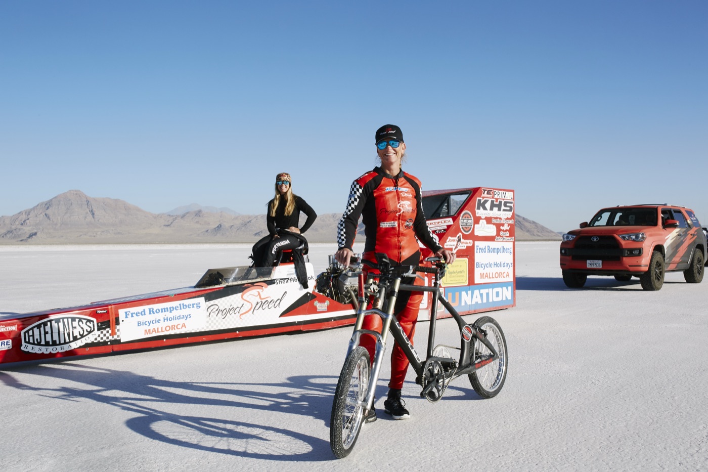 Denise Mueller with her custom bicycle, driver Shea Holbrook and the Project Speed dragster