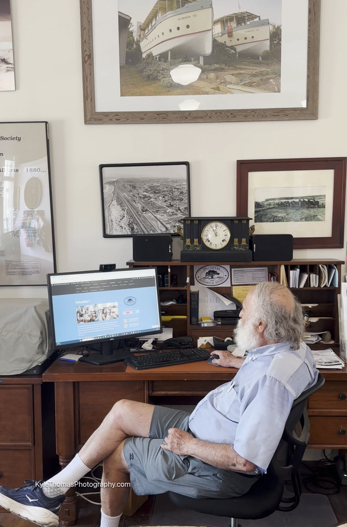 Hillel Schwartz at his desk in the Encinitas Historical Society archive, surrounded by framed historical photographs