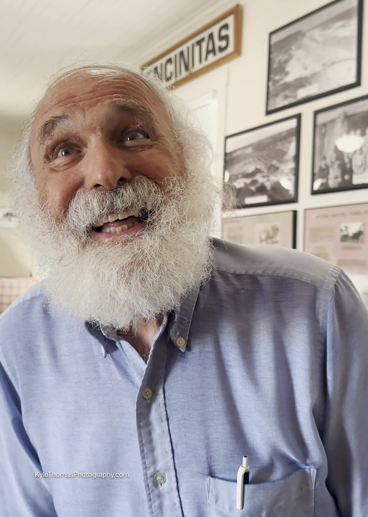 Portrait of Hillel Schwartz smiling, framed historical photographs behind him