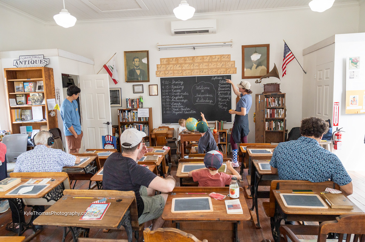 Visitors seated at antique school desks during an Independence Days session at the 1883 Schoolhouse