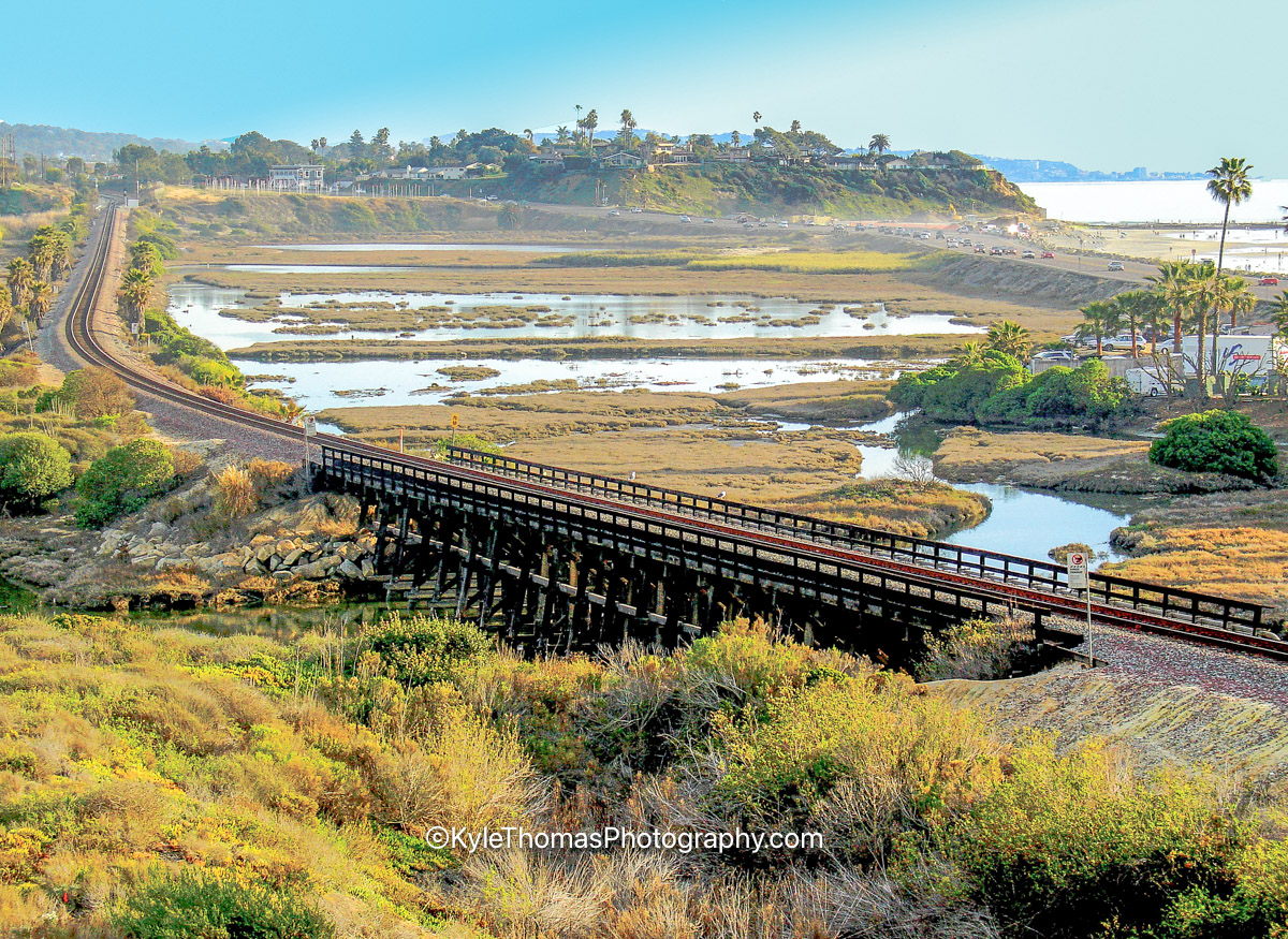 The wooden railroad trestle carrying the tracks across San Elijo Lagoon, with the Cardiff bluffs and the ocean beyond, Cardiff-by-the-Sea California